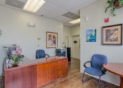Thumbnail 3 of 11 - a doctors office with a wooden reception desk and blue chairs