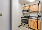 Thumbnail 6 of 10 - a kitchen with a stove and microwave and wooden cabinets