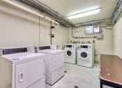 Thumbnail 3 of 10 - a laundry room with four washing machines and a table