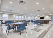 Thumbnail 12 of 15 - a large dining room with tables and chairs and a television