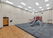 Thumbnail 40 of 50 - A gym with a slide and a wooden floor.