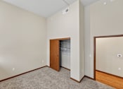 Thumbnail 17 of 50 - A room with a carpeted floor and a wooden door leading to a laundry room.