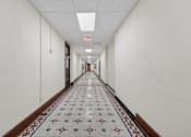 Thumbnail 45 of 50 - A long hallway with a tiled floor and white walls.