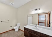 Thumbnail 19 of 50 - A bathroom with a toilet, sink, and mirror.