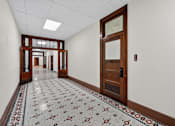 Thumbnail 49 of 50 - A hallway with a tiled floor and a brown door.