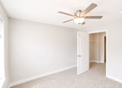 Thumbnail 6 of 28 - A room with a ceiling fan and carpeted floor.