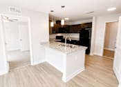 Thumbnail 1 of 28 - A kitchen with a black refrigerator and white cabinets.