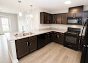 Thumbnail 4 of 28 - A kitchen with black appliances and brown cabinets.