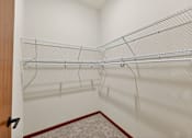 Thumbnail 14 of 50 - A walk-in closet with a carpeted floor and a wooden door.