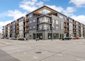 Thumbnail 49 of 52 - A large apartment building with a parking lot in front.