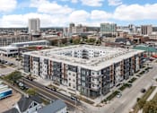 Thumbnail 51 of 52 - A large apartment complex is surrounded by a parking lot and other buildings.