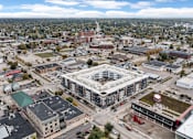 Thumbnail 46 of 52 - A large building with a green roof is surrounded by other buildings and construction.