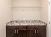 Thumbnail 12 of 43 - an empty laundry room with two cabinets and a granite counter top at 5Fifty5, Des Moines, IA 50309  