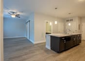 Thumbnail 10 of 65 - A kitchen with a fan on the ceiling and a countertop with cabinets.