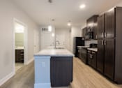 Thumbnail 8 of 65 - A kitchen with a marble island and dark wood cabinets.