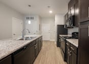 Thumbnail 24 of 65 - A kitchen with dark wood cabinets and a granite countertop.