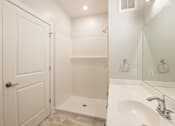 Thumbnail 13 of 65 - A white bathroom with a door, sink, and mirror.