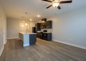 Thumbnail 1 of 65 - A room with a ceiling fan and a kitchen area with a counter and cabinets.