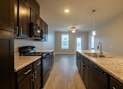 Thumbnail 4 of 65 - A kitchen with black cabinets and a granite countertop.