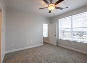 Thumbnail 33 of 65 - A room with a ceiling fan and carpeted floor.