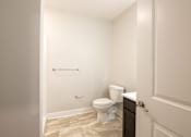 Thumbnail 40 of 65 - A white toilet sits in a bathroom next to a white door.