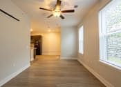 Thumbnail 11 of 65 - A room with a ceiling fan and light fixture, wooden flooring, and a window with blinds.