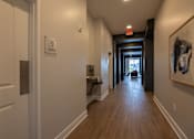 Thumbnail 49 of 65 - A hallway with a white door and a brown floor.