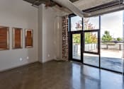 Thumbnail 5 of 23 - Living room with a large window and a door to a patio at Ballyard Lofts, Iowa , 50309