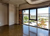 Thumbnail 7 of 23 - Living room with floor to ceiling windows and a city view at Ballyard Lofts, Indigo Living, IA, Iowa , 50309