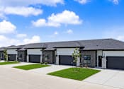 Thumbnail 1 of 53 - A row of houses with garages and driveways.