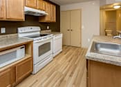 Thumbnail 3 of 20 - A kitchen with wooden cabinets and a white stove top oven at Cedarbrooke Place , Norwalk, IA, 50211