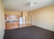 Thumbnail 9 of 16 - Empty room with a ceiling fan and a kitchen area in the background.at Cottages at Johnston Commons, Johnston, IA  