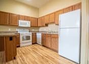 Thumbnail 12 of 16 - A kitchen with wooden cabinets and a white refrigerator.at Cottages at Johnston Commons, Iowa, 50131