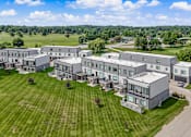 Thumbnail 33 of 34 - A large, modern building complex with a green lawn in front.