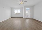 Thumbnail 23 of 52 - A room with a ceiling fan and light, hardwood floors, and a window with a view of the outside.