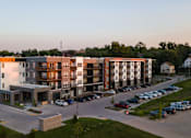 Thumbnail 17 of 65 - A modern apartment complex with a parking lot in front.