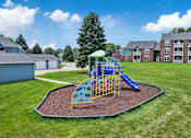 Thumbnail 46 of 53 - A playground with a yellow and blue slide in the middle of a grassy area.