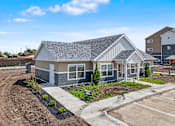 Thumbnail 30 of 53 - A house with a grey roof and a white garage door is surrounded by a parking lot.