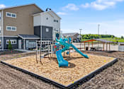 Thumbnail 40 of 53 - A playground with a blue slide in the foreground and houses in the background.