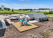 Thumbnail 38 of 53 - A playground with a blue slide is in the foreground of a construction site.