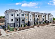 Thumbnail 42 of 53 - A row of new townhouses with a parking lot in front.