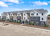 Thumbnail 41 of 53 - A row of new townhouses with a parking lot in front.