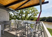 Thumbnail 37 of 42 - A patio with chairs and a table overlooking a river. at Eagle View Lofts, Des Moines, Iowa