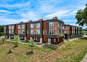 Thumbnail 30 of 42 - A row of red and brown townhouses with green trees in front. at Eagle View Lofts, Des Moines, IA