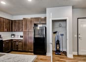 Thumbnail 30 of 31 - A kitchen with a black fridge and wooden cabinets.