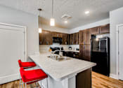 Thumbnail 1 of 31 - A kitchen with a white countertop and red chairs.