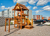 Thumbnail 13 of 31 - A wooden playhouse sits in the foreground of a residential area.