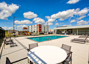 Thumbnail 7 of 31 - A pool area with a table and chairs.