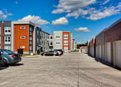Thumbnail 9 of 31 - A parking lot in front of a row of apartment buildings.