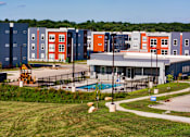 Thumbnail 8 of 31 - A large building with a pool in front of it.